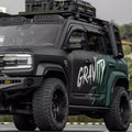 Matte black and dark green rugged off-road SUV featuring heavy-duty roof racks and all-terrain tires.
