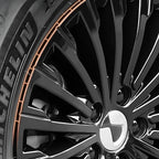 Close-up of a glossy black alloy wheel with a distinctive orange accent rim line.