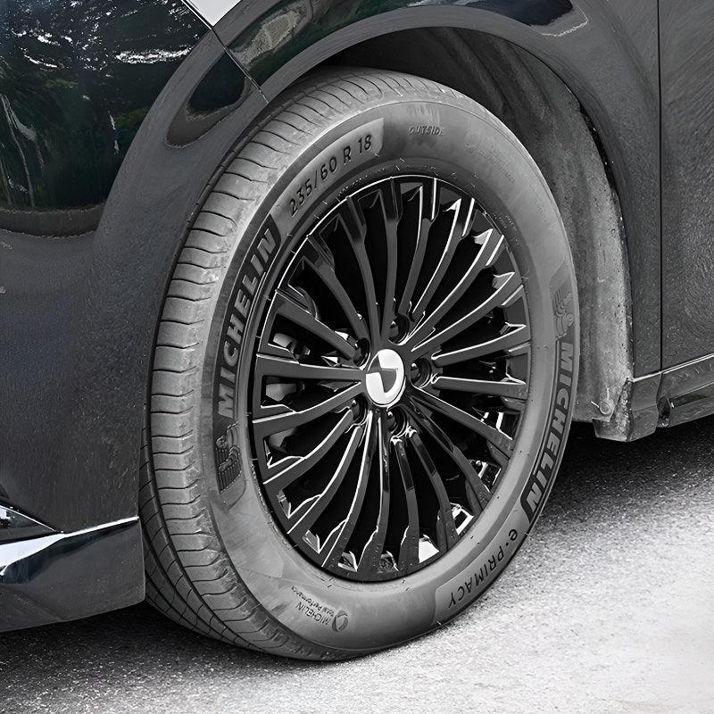 Close-up of a black Michelin Primacy tire mounted on a multi-spoke black alloy rim of a dark vehicle.