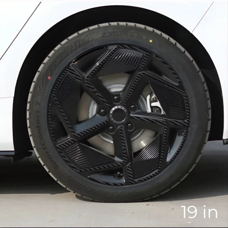 A 19-inch black multi-spoke alloy wheel with a textured geometric design on a white car.