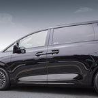 Side profile of a sleek black BYD minivan parked outdoors under a cloudy sky.