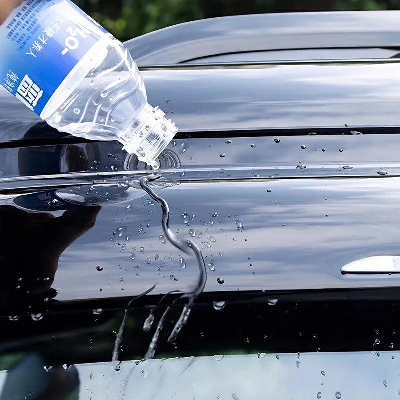 Water pouring onto a glossy black hydrophobic car paint protection film.