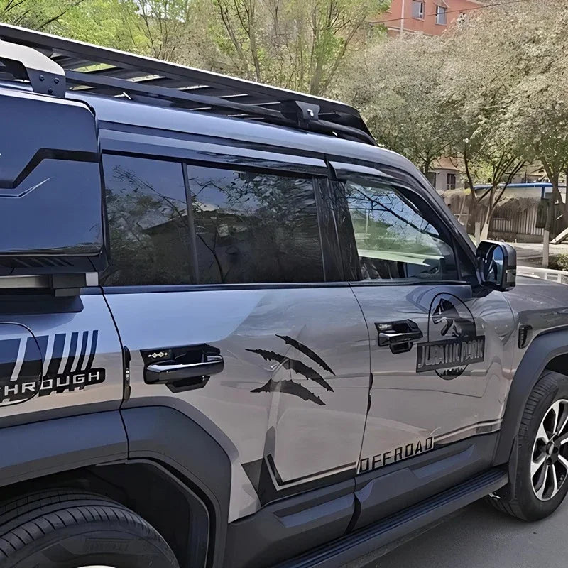 Silver BYD offroad vehicle featuring black Jurassic Park claw mark decals and roof rack.