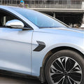 Black carbon fiber textured fender vent accessory for a light blue sedan.