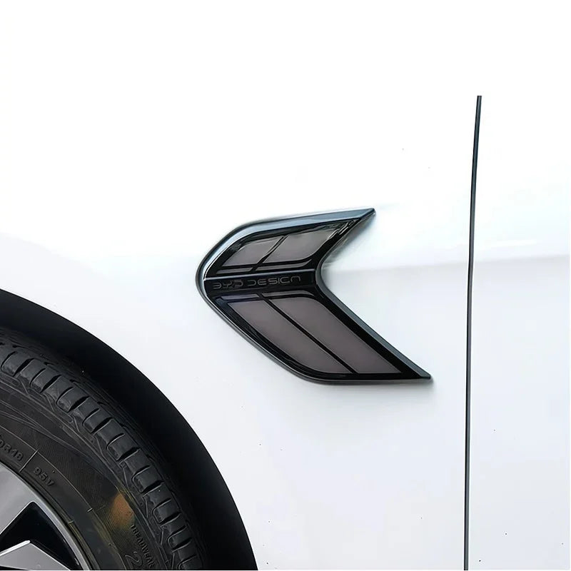 Sleek black aerodynamic fender vent with a glossy finish installed on a white car body.
