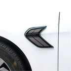 Sleek black aerodynamic fender vent with a glossy finish installed on a white car body.