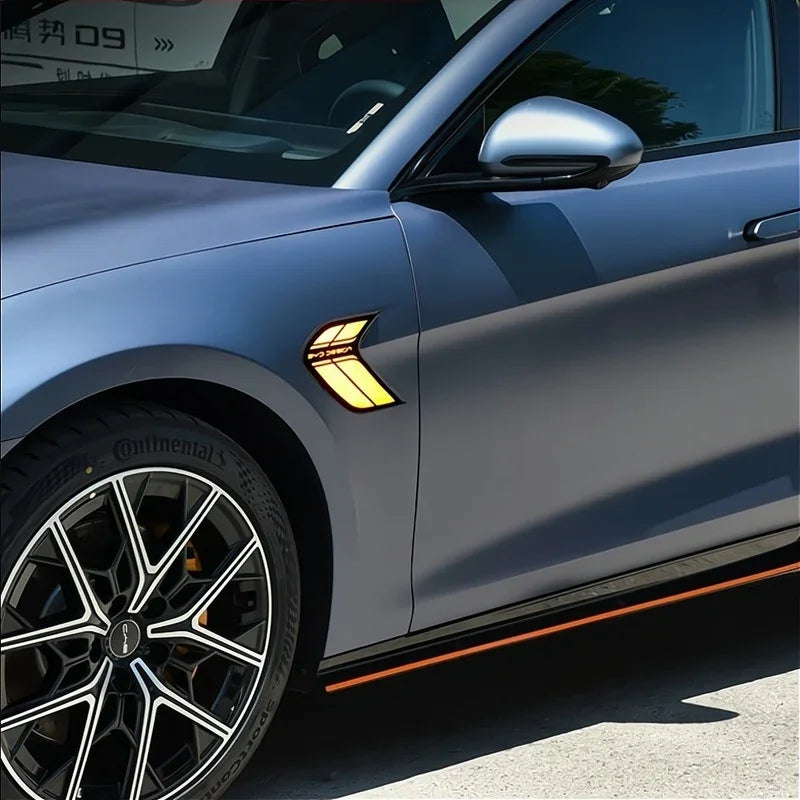 Matte blue BYD car with amber side marker light and black trim with orange accent.