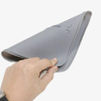 Flexible grey silicone car floor mat being bent to demonstrate durability and material flexibility.