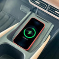 Red-edged smartphone charging on a black carbon fiber texture wireless charging pad in a car.