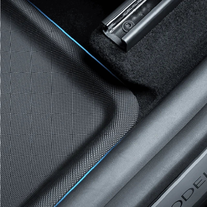 Black textured TPE car floor mat with blue edge stitching for durable interior protection.
