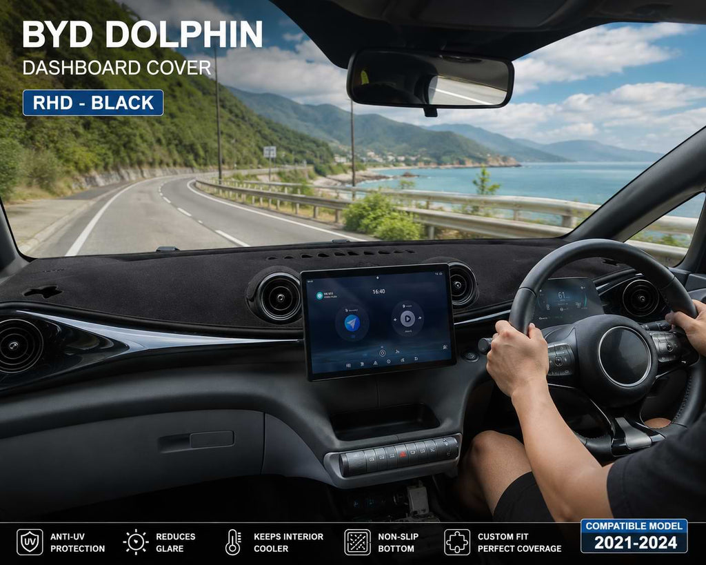 Driver's view inside a BYD Dolphin with a black RHD dashboard cover installed while driving on a scenic coastal road, compatible with 2021-2024 models.