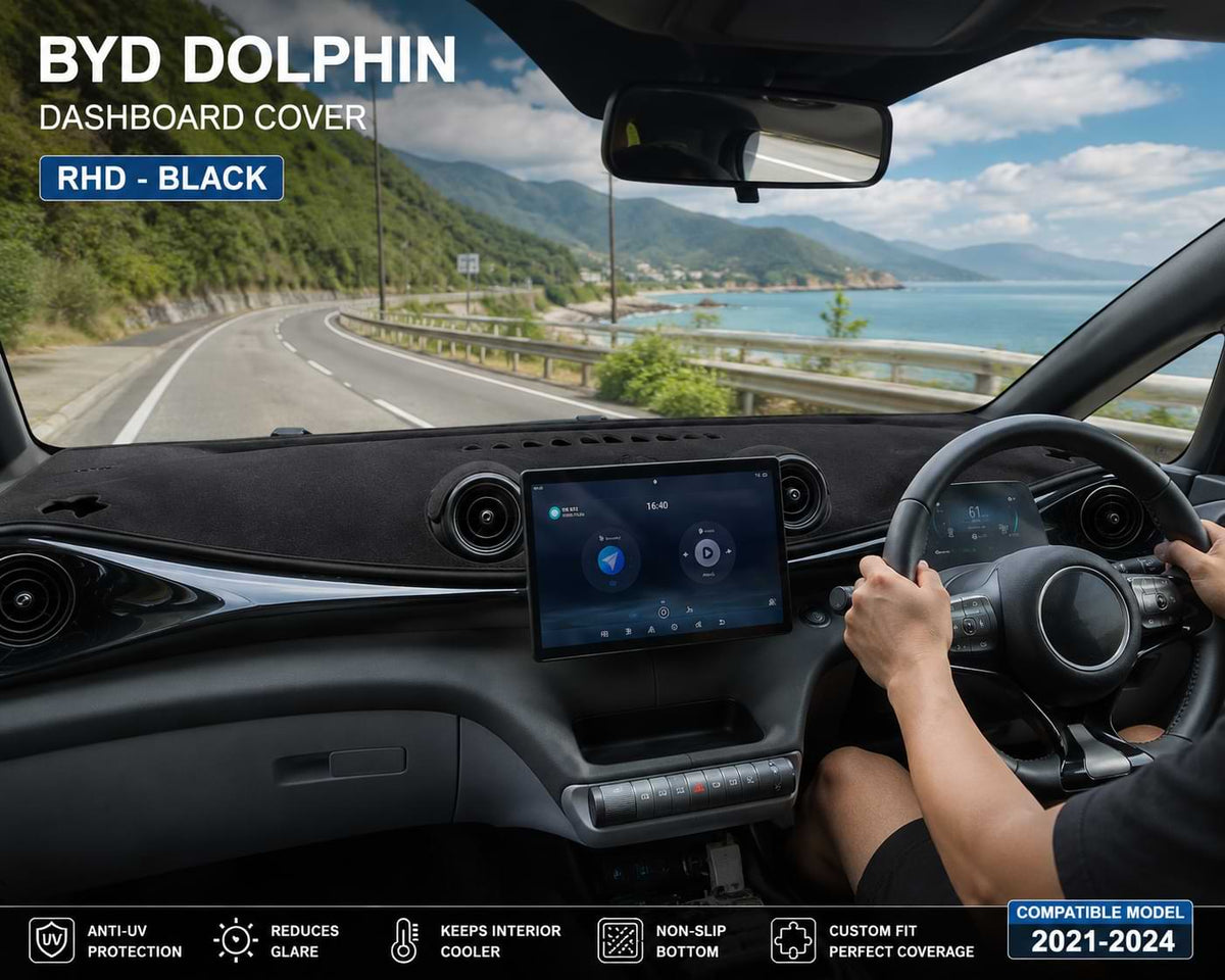 Driver's view inside a BYD Dolphin with a black RHD dashboard cover installed while driving on a scenic coastal road, compatible with 2021-2024 models.