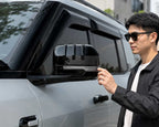 Model inspecting the BYD Leopard 8 2024-2025 rearview mirror fitted with a gloss black ABS mirror protection cover.