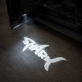 BYD Shark 2025 LED door welcome light projecting Shark logo onto the ground at night