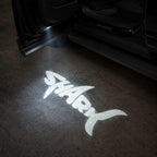 BYD Shark 2025 LED door welcome light projecting Shark logo onto the ground at night