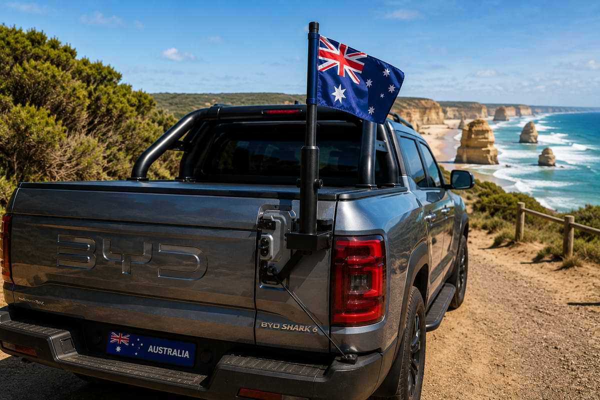 BYD Shark 6 with Australian flagpole mount driving near coastal road scenery