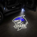 Blue Shark logo LED welcome light projection beside BYD Shark vehicle at night