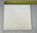 White pleated cabin air filter for BYD cars shown with a measuring tape for size reference.