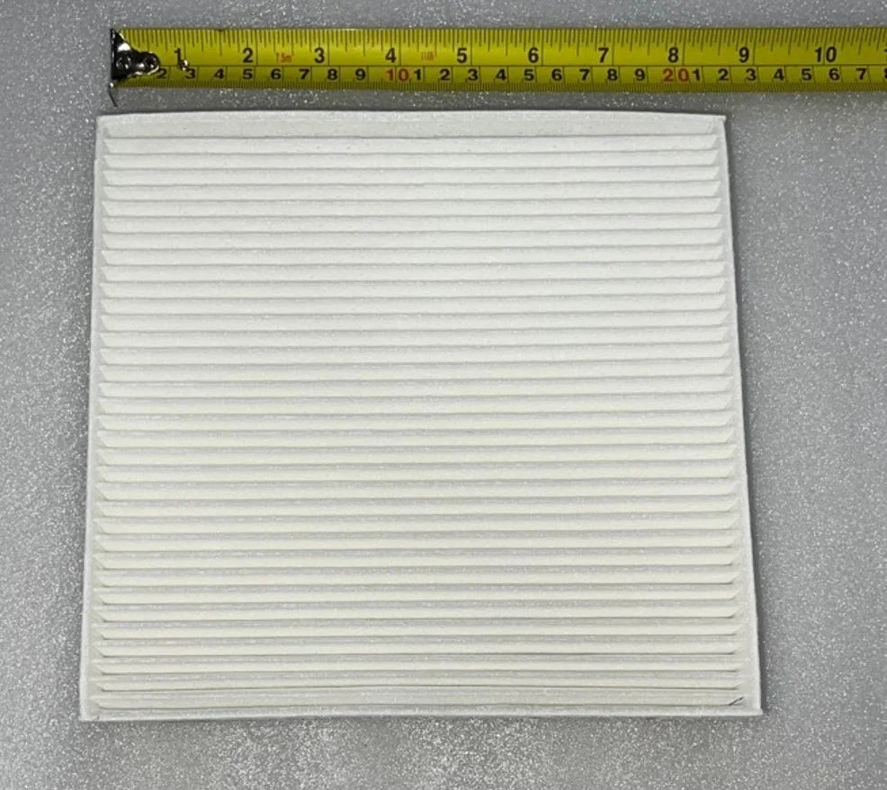 White pleated cabin air filter for BYD cars shown with a measuring tape for size reference.