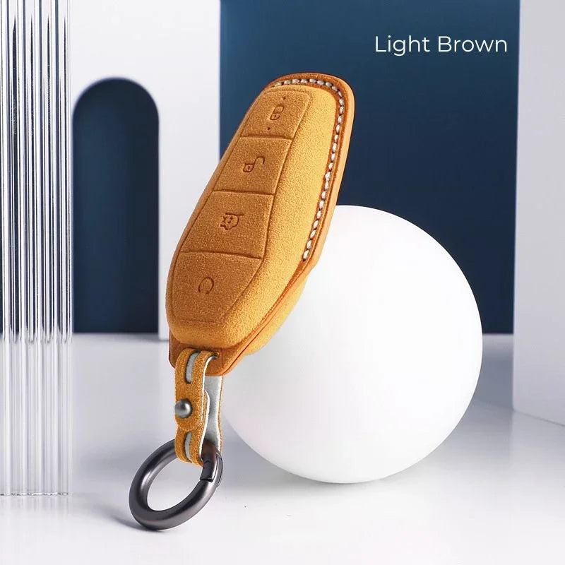 Light brown leather car key cover with white stitching and metal key ring